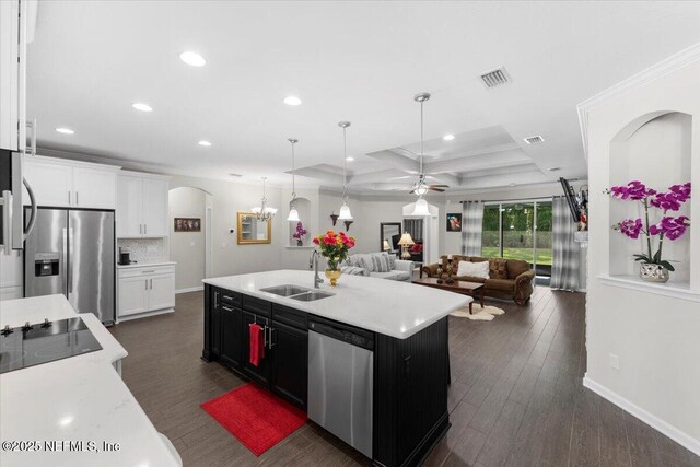 kitchen with appliances with stainless steel finishes, a sink, open floor plan, arched walkways, and light countertops