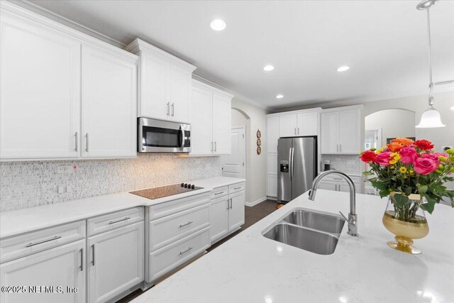 kitchen featuring stainless steel appliances, a sink, arched walkways, white cabinetry, and recessed lighting
