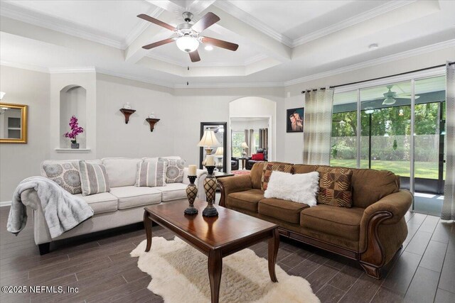 living area with arched walkways, a ceiling fan, dark wood finished floors, ornamental molding, and beam ceiling