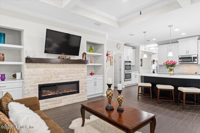 living area featuring ornamental molding, a stone fireplace, dark wood-style flooring, built in features, and recessed lighting