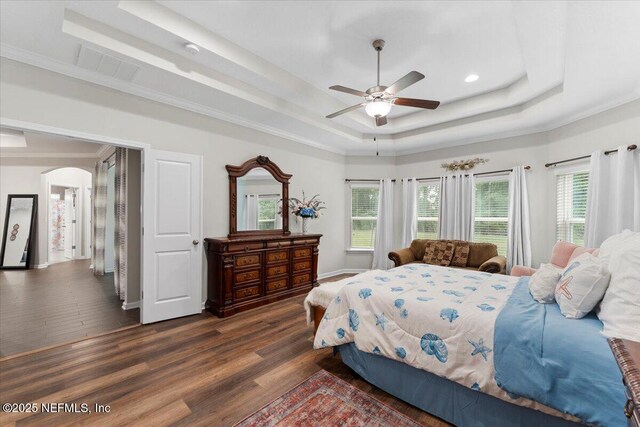 bedroom featuring a raised ceiling, arched walkways, dark wood-style flooring, baseboards, and recessed lighting