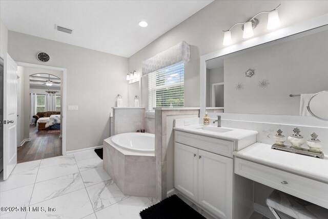 ensuite bathroom featuring healthy amount of natural light, a bath, marble finish flooring, vanity, and recessed lighting