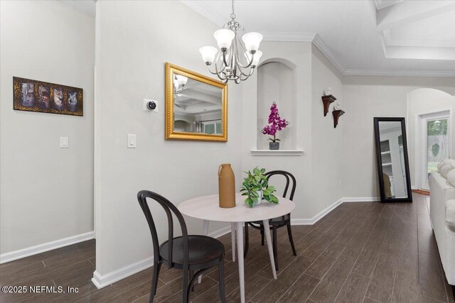 dining room with dark wood-style flooring, a chandelier, baseboards, ornamental molding, and arched walkways