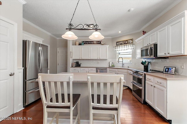 11921 Loretto Square Dr S, Jacksonville, FL 32223 - kitchen featuring stainless steel appliances, a center island, white cabinetry, a textured ceiling, and crown molding