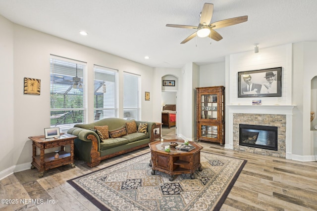 1009 Welaka Way, Saint Augustine, FL 32092 - living room featuring wood finished floors, ceiling fan, a stone fireplace, arched walkways, and baseboards