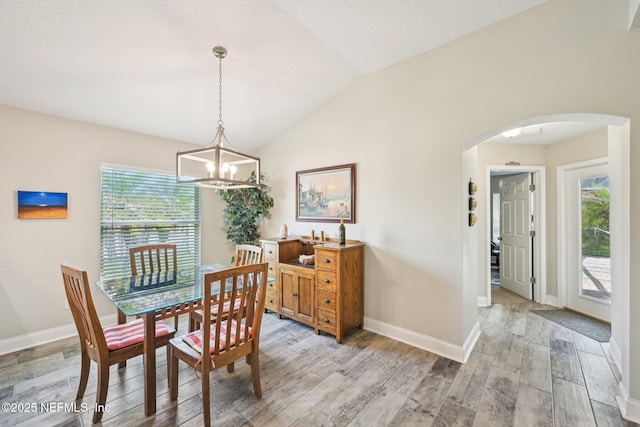 1009 Welaka Way, Saint Augustine, FL 32092 - dining area with arched walkways, light wood-style flooring, vaulted ceiling, a chandelier, and plenty of natural light