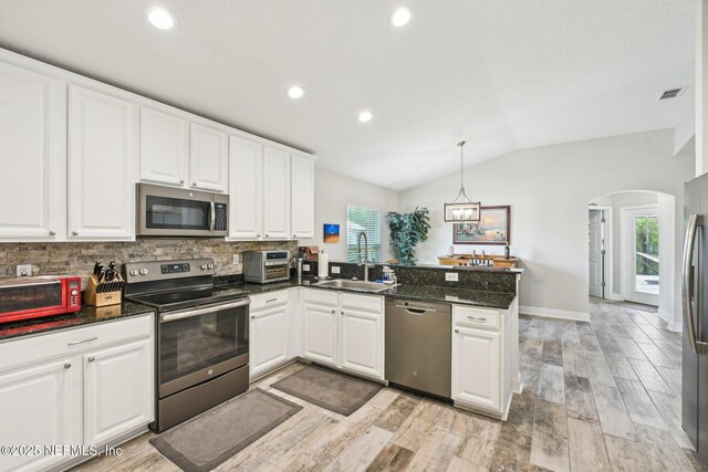 1009 Welaka Way, Saint Augustine, FL 32092 - kitchen featuring appliances with stainless steel finishes, a sink, arched walkways, a peninsula, and white cabinetry