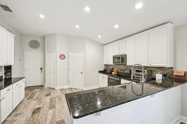 1009 Welaka Way, Saint Augustine, FL 32092 - kitchen featuring stainless steel appliances, light wood finished floors, dark stone counters, recessed lighting, and decorative backsplash
