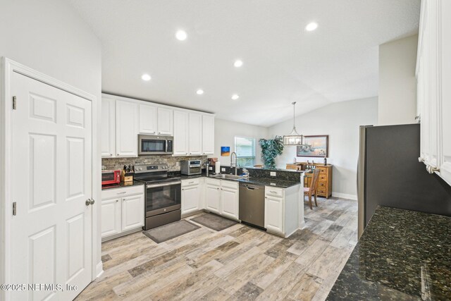 1009 Welaka Way, Saint Augustine, FL 32092 - kitchen featuring stainless steel appliances, a sink, a peninsula, lofted ceiling, and white cabinets