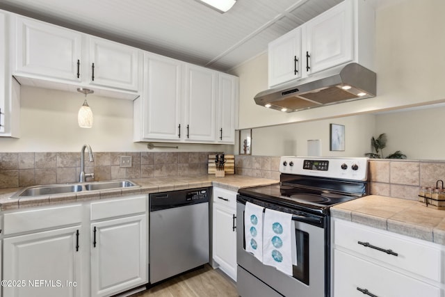 925 Tarpon Ave Unit 16, Fernandina Beach, FL 32034 - kitchen featuring appliances with stainless steel finishes, under cabinet range hood, a sink, white cabinetry, and light wood-style floors