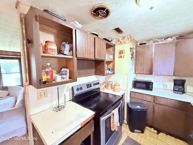 4507 Harbor View Dr, Jacksonville, FL 32208 - kitchen featuring stainless steel electric range oven, black microwave, open shelves, light countertops, and a textured ceiling