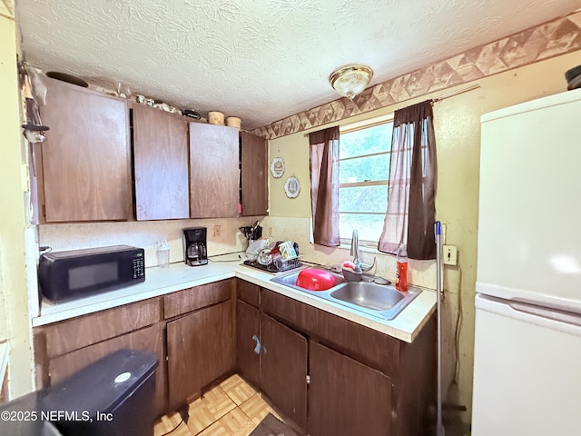 4507 Harbor View Dr, Jacksonville, FL 32208 - kitchen featuring freestanding refrigerator, black microwave, light countertops, a sink, and a textured ceiling