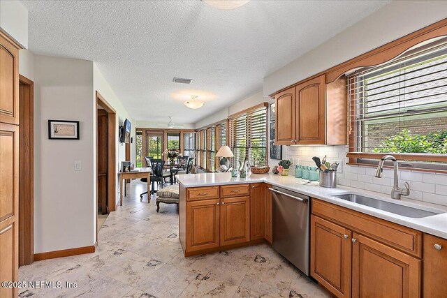 73 Waterbridge Pl, Ponte Vedra Beach, FL 32082 - kitchen with dishwasher, a sink, a peninsula, brown cabinetry, and a textured ceiling