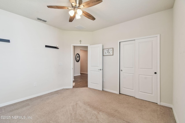 unfurnished bedroom featuring carpet flooring, a closet, baseboards, and a ceiling fan