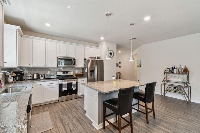 kitchen with stainless steel appliances, a sink, light wood-style floors, white cabinets, and recessed lighting