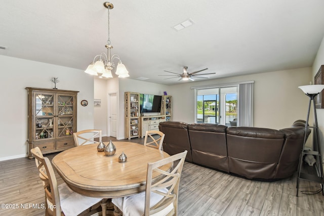 dining area featuring light wood-type flooring, a chandelier, a ceiling fan, and baseboards