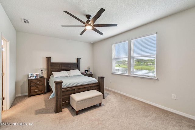 bedroom featuring light colored carpet, baseboards, a ceiling fan, and a textured ceiling