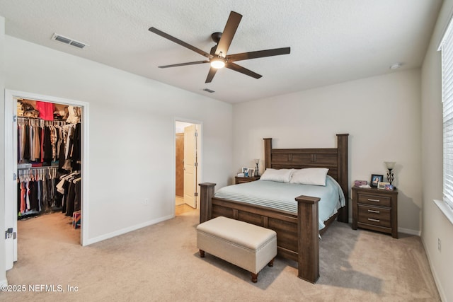 bedroom featuring light carpet, a walk in closet, a closet, and baseboards