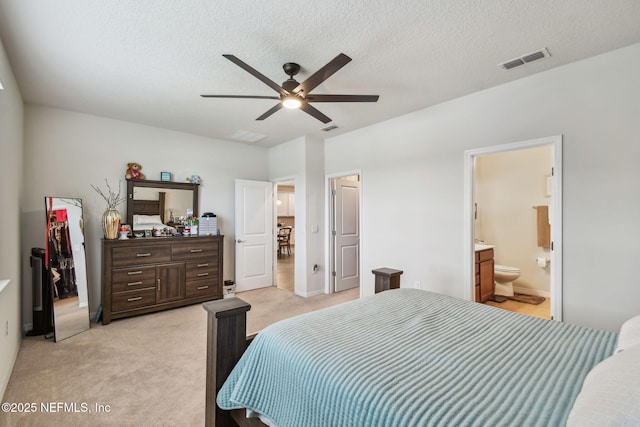 bedroom with light colored carpet, a textured ceiling, ensuite bath, and ceiling fan