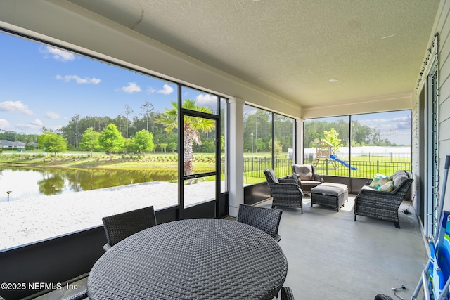 sunroom / solarium featuring an outdoor hangout area, a water view, view of wooded area, and outdoor dining area