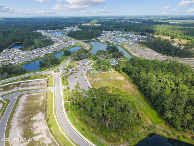 aerial view of property's location featuring a nearby body of water and a heavily wooded area