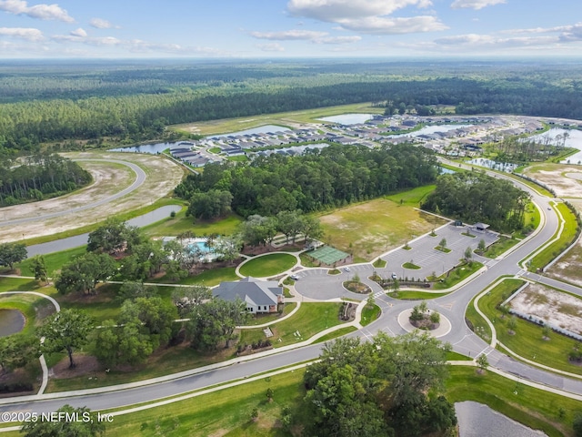 aerial view of property and surrounding area with a forest and a nearby body of water