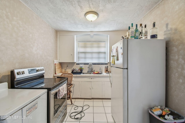 2660 Gale Ct, Jacksonville, FL 32204 - kitchen with freestanding refrigerator, stainless steel range with electric stovetop, a sink, a textured ceiling, and light tile patterned flooring