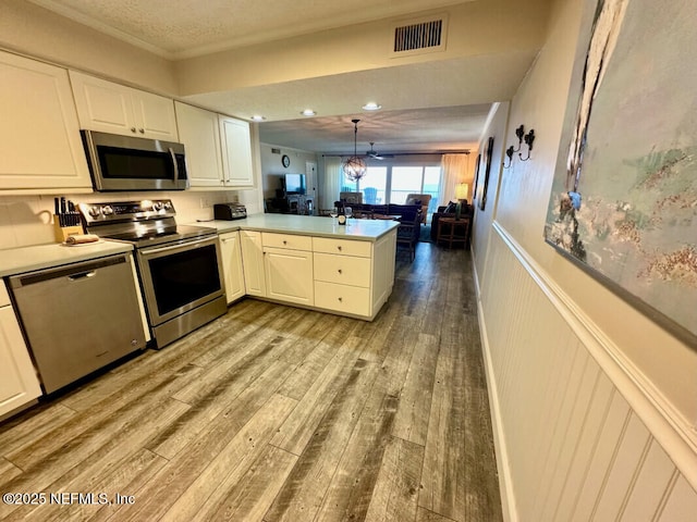 3240 Fletcher Ave Unit 665, Fernandina Beach, FL 32034 - kitchen with stainless steel appliances, a peninsula, light wood-style floors, white cabinetry, and open floor plan