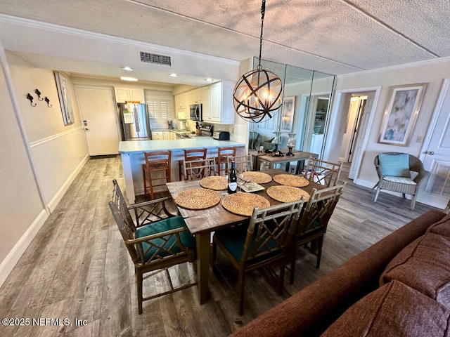 3240 Fletcher Ave Unit 665, Fernandina Beach, FL 32034 - dining area featuring ornamental molding, light wood-style flooring, a textured ceiling, a chandelier, and baseboards