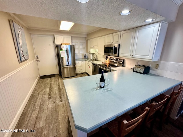 3240 Fletcher Ave Unit 665, Fernandina Beach, FL 32034 - kitchen with stainless steel appliances, light wood-type flooring, a peninsula, white cabinets, and light countertops