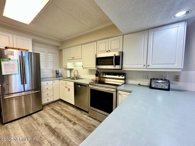 3240 Fletcher Ave Unit 665, Fernandina Beach, FL 32034 - kitchen with appliances with stainless steel finishes, a sink, light wood-type flooring, white cabinetry, and a textured ceiling