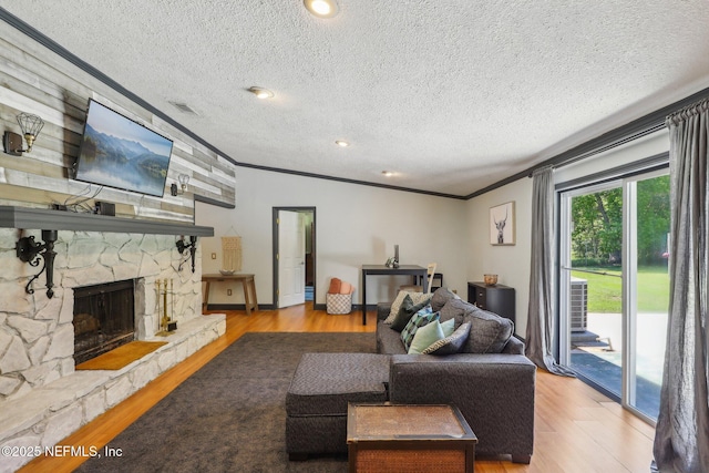 4033 Lazy Hollow Ln N, Jacksonville, FL 32257 - living room featuring ornamental molding, wood finished floors, a textured ceiling, and a stone fireplace