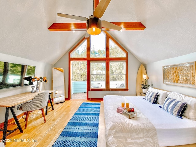 bedroom with a textured ceiling, wood finished floors, and lofted ceiling