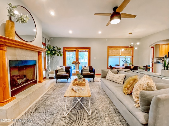 living area featuring arched walkways, a ceiling fan, recessed lighting, healthy amount of natural light, and a fireplace