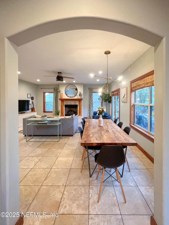 dining room with light tile patterned floors, a fireplace, recessed lighting, and a chandelier