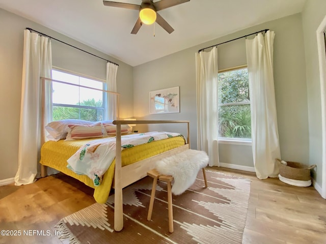 bedroom with light wood finished floors, baseboards, and a ceiling fan