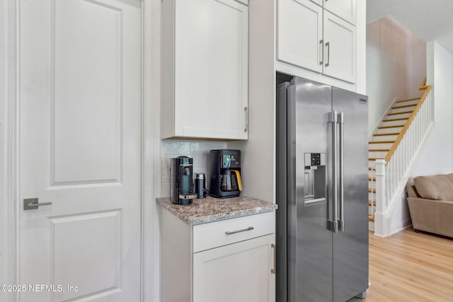 355 Caiden Dr, Ponte Vedra, FL 32081 - kitchen with stainless steel fridge with ice dispenser, light wood finished floors, white cabinets, and light stone countertops