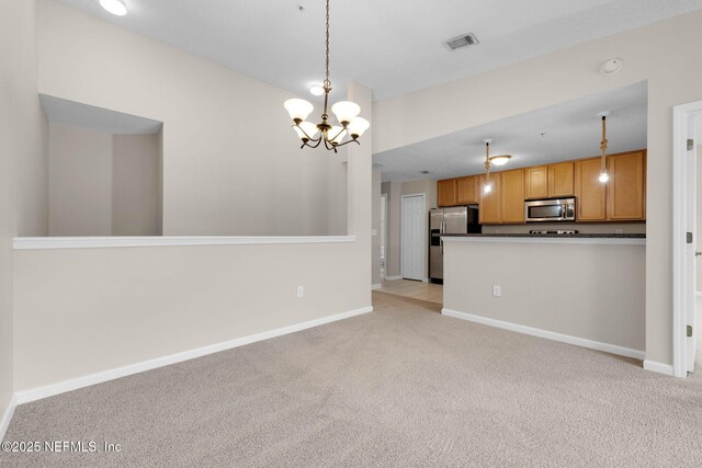 13856 Herons Landing Way Unit 11-7, Jacksonville, FL 32224 - kitchen featuring appliances with stainless steel finishes, dark countertops, a chandelier, light carpet, and decorative light fixtures