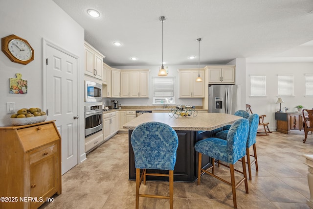 285 Yearling Blvd, Saint Johns, FL 32259 - kitchen featuring appliances with stainless steel finishes, a kitchen island, a kitchen bar, cream cabinets, and pendant lighting