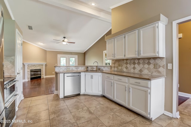 kitchen with stainless steel dishwasher, a sink, ceiling fan, tasteful backsplash, and white cabinets