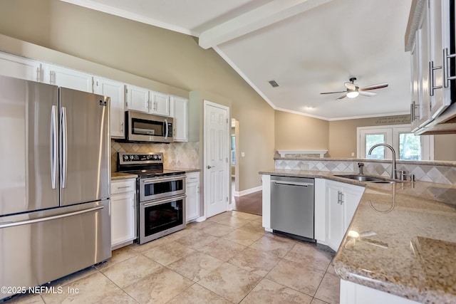 kitchen with appliances with stainless steel finishes, a sink, ceiling fan, backsplash, and white cabinetry
