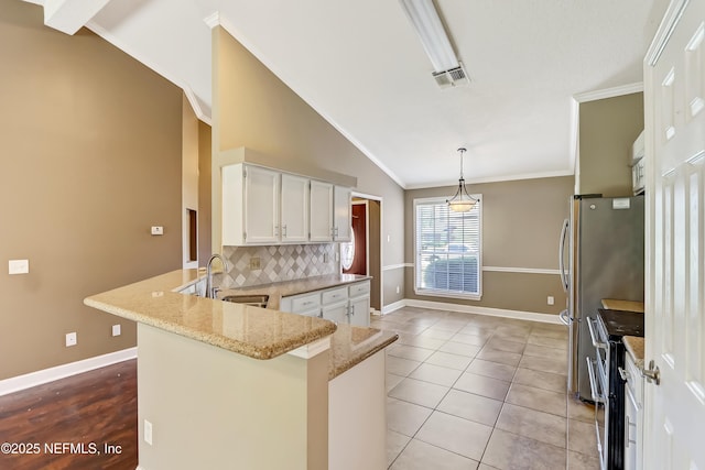 kitchen with range with two ovens, a sink, a peninsula, backsplash, and vaulted ceiling