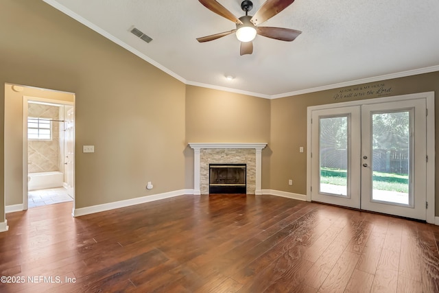 unfurnished living room featuring a ceiling fan, dark wood-style floors, french doors, ornamental molding, and a fireplace