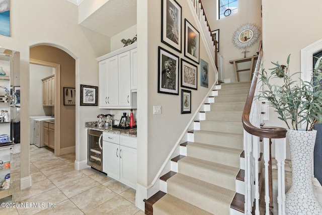 110 Heron Dr, Palm Coast, FL 32137 - staircase featuring beverage cooler, arched walkways, washer and dryer, and a bar