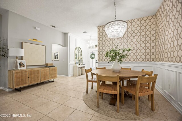 217 Willow Winds Pkwy, Saint Johns, FL 32259 - dining room with a chandelier, arched walkways, a wainscoted wall, light tile patterned flooring, and a decorative wall