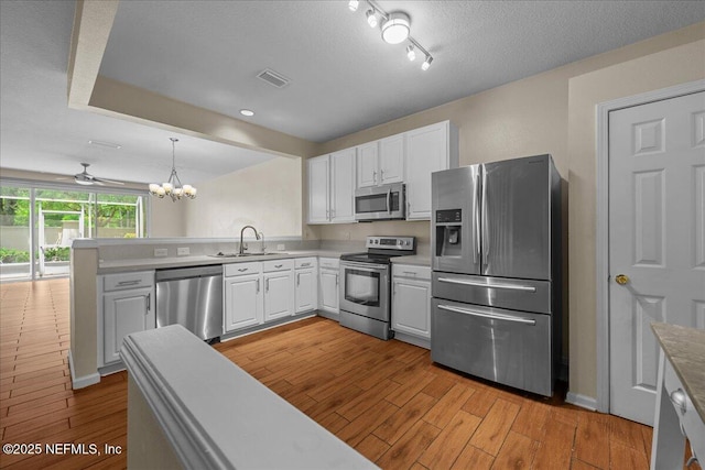 7990 Baymeadows Rd Unit 1305, Jacksonville, FL 32256 - kitchen with stainless steel appliances, a sink, a peninsula, light wood-style floors, and white cabinetry
