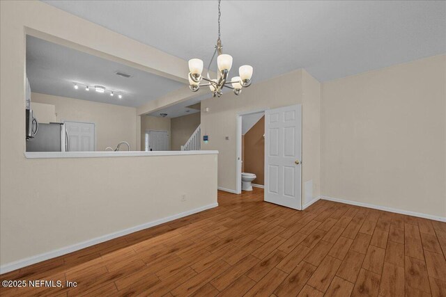 7990 Baymeadows Rd Unit 1305, Jacksonville, FL 32256 - unfurnished living room featuring wood finished floors, a chandelier, baseboards, and stairs