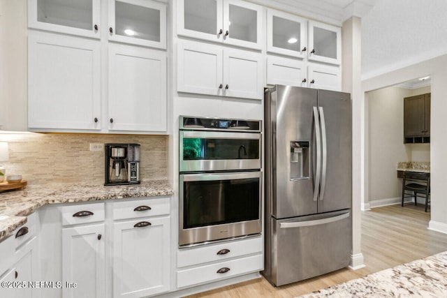 250 Ponder Cir, Yulee, FL 32097 - kitchen with appliances with stainless steel finishes, white cabinets, backsplash, light stone counters, and ornamental molding