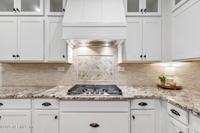 250 Ponder Cir, Yulee, FL 32097 - kitchen with custom exhaust hood, white cabinets, stainless steel gas stovetop, and backsplash