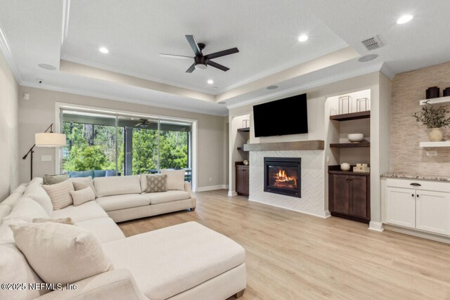 250 Ponder Cir, Yulee, FL 32097 - living area featuring a raised ceiling, light wood finished floors, a ceiling fan, a tiled fireplace, and baseboards